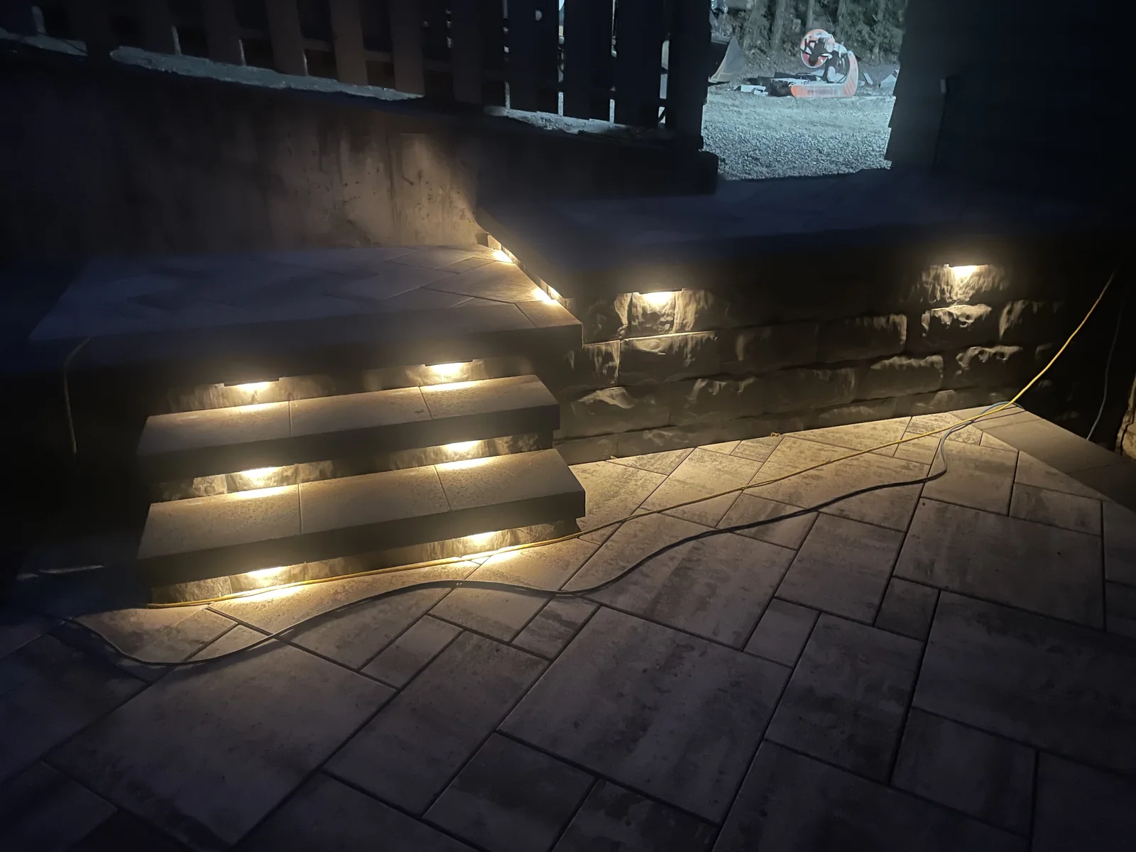 Lit steps and paver patio at night