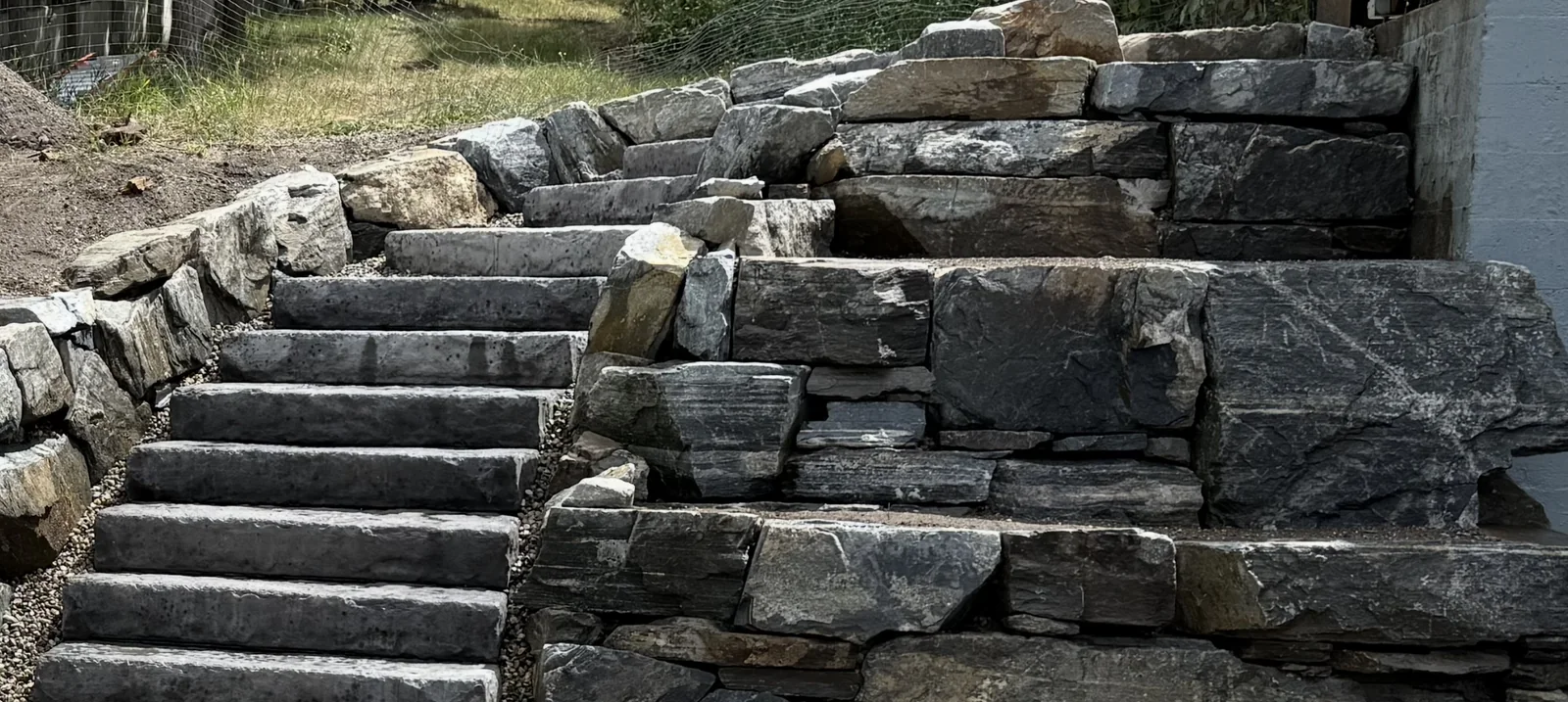 Cut stone stair run between stacked natural stone walls