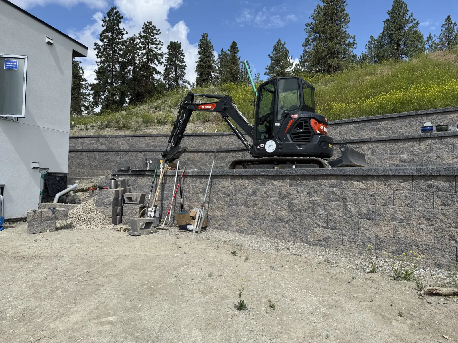 Mini excavator on a new two tier block retaining wall