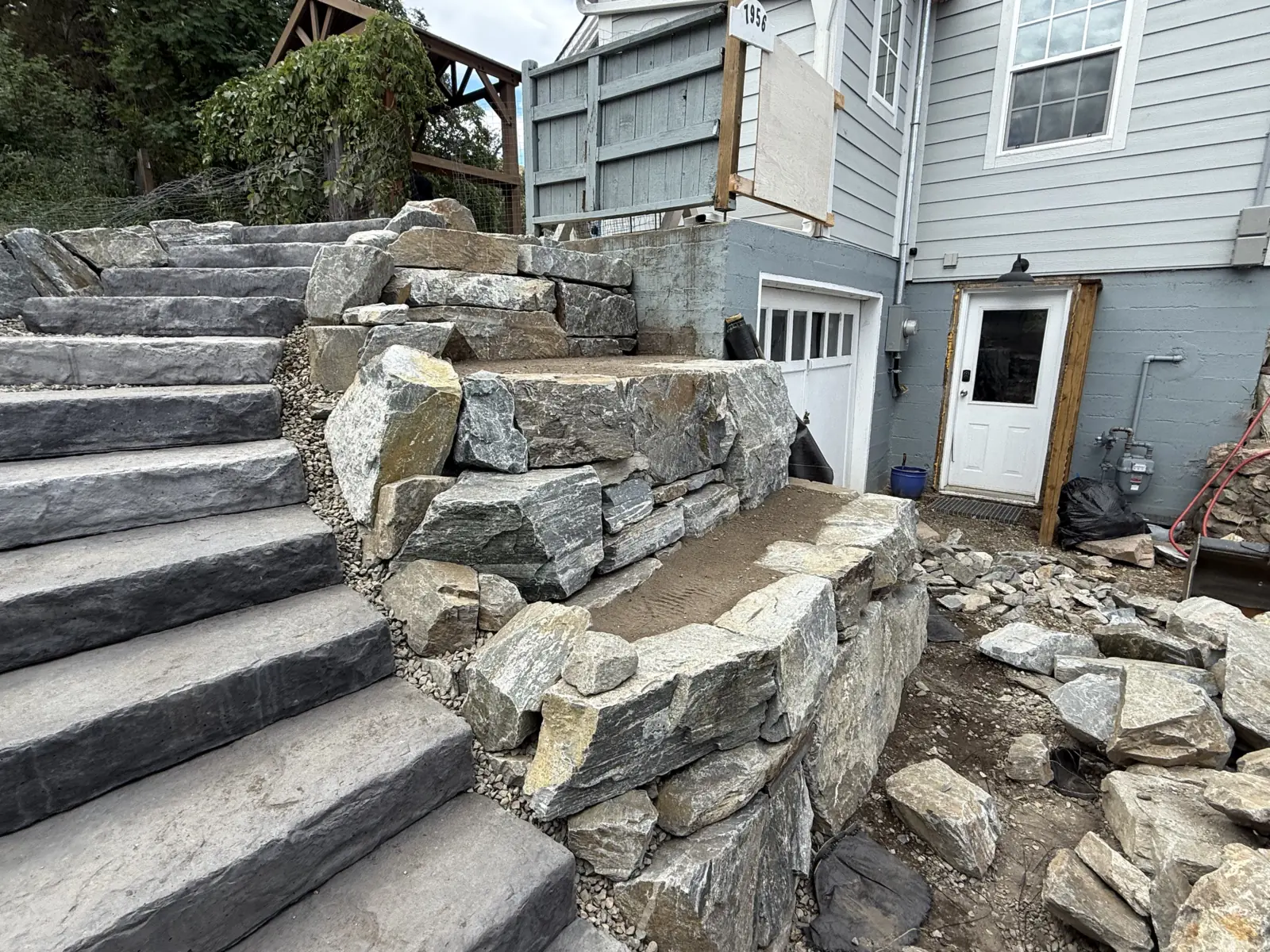 Natural stone staircase and boulder retaining wall beside a home