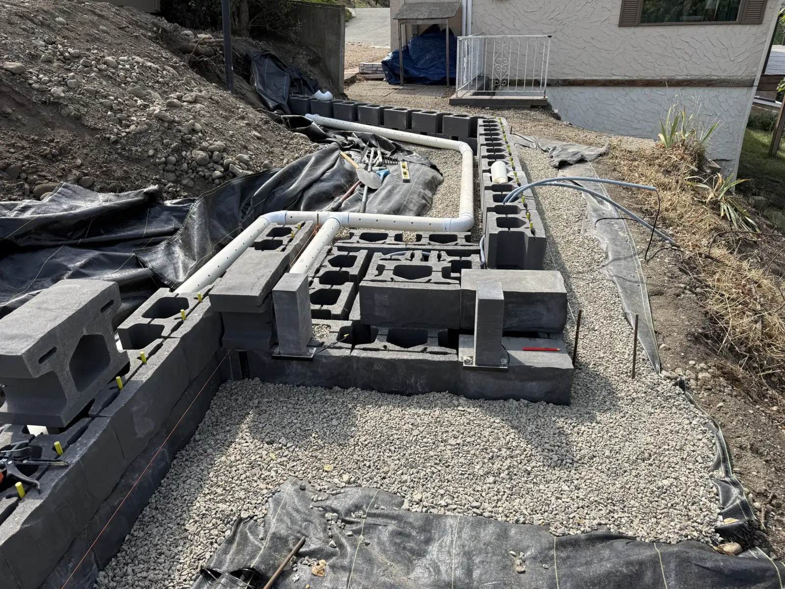 Block wall base course with drain pipe and conduit in place