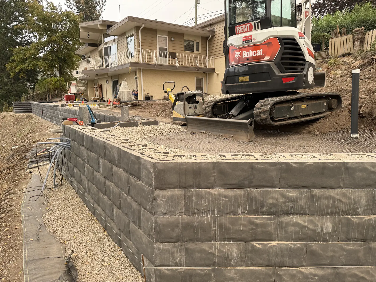 Tall block retaining wall with a track loader working above it