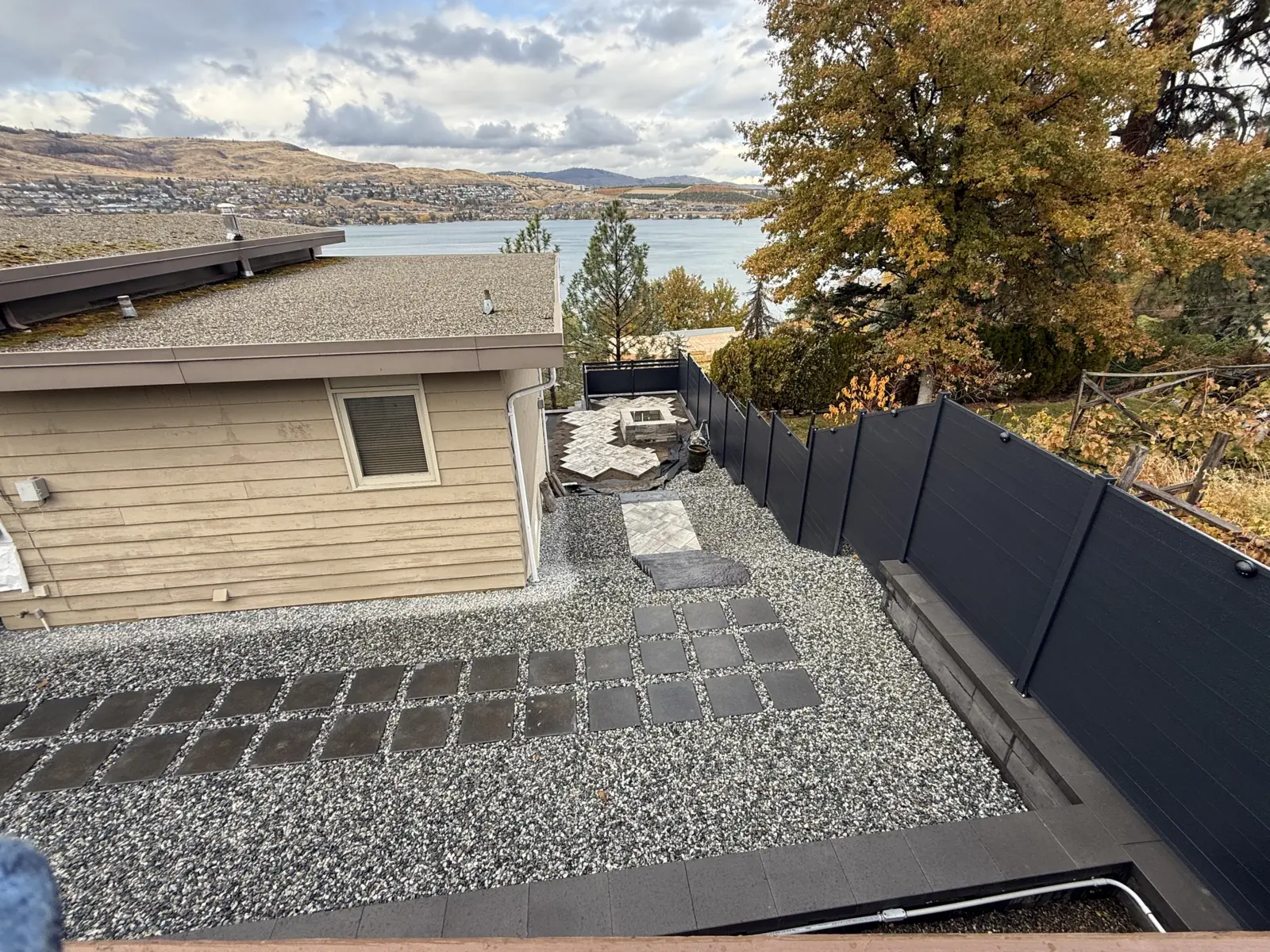 Stepping stone path through gravel with black fencing and a lake view