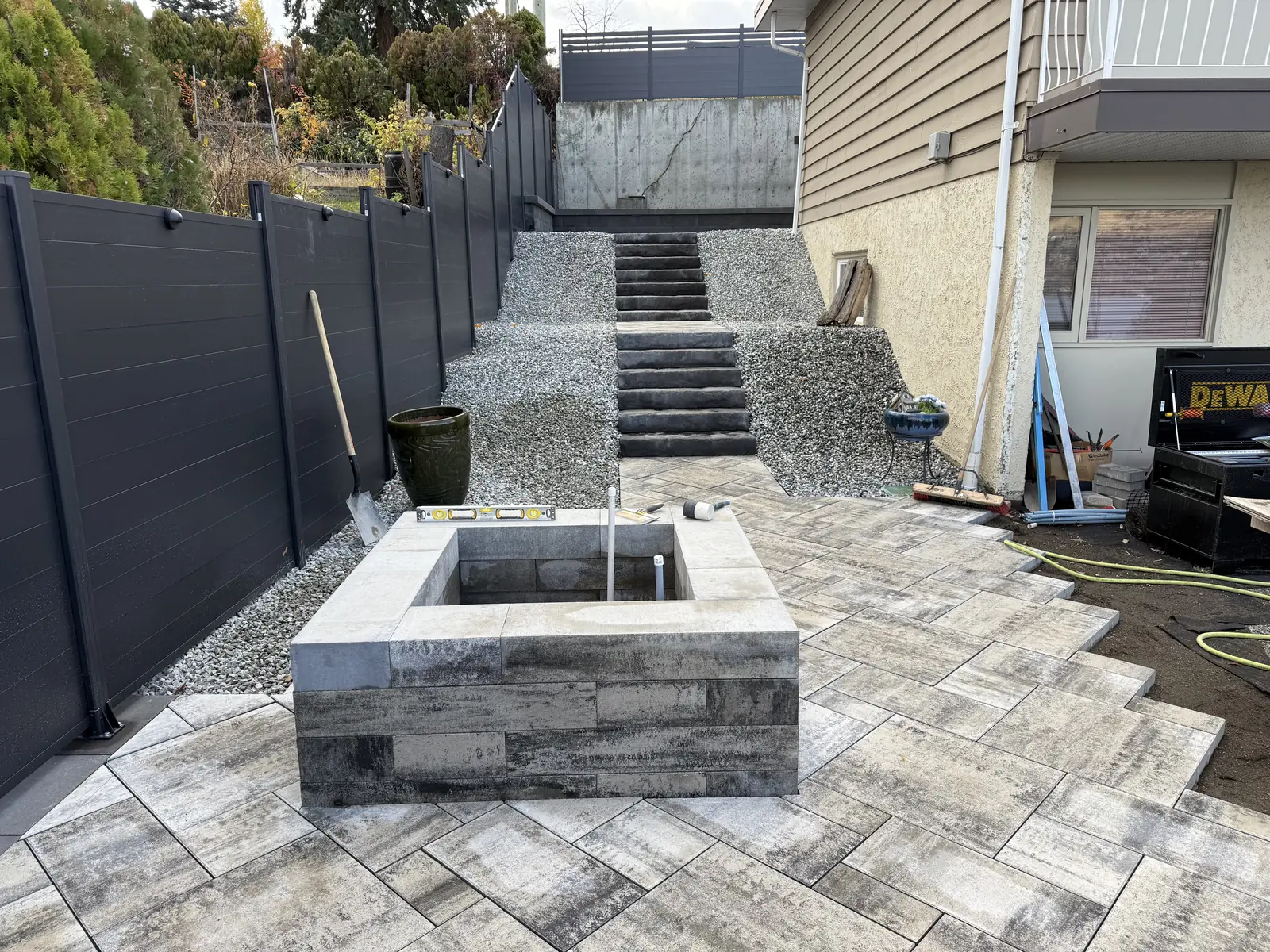 Paver patio with a built fire pit, gravel beds and stairs up the side yard