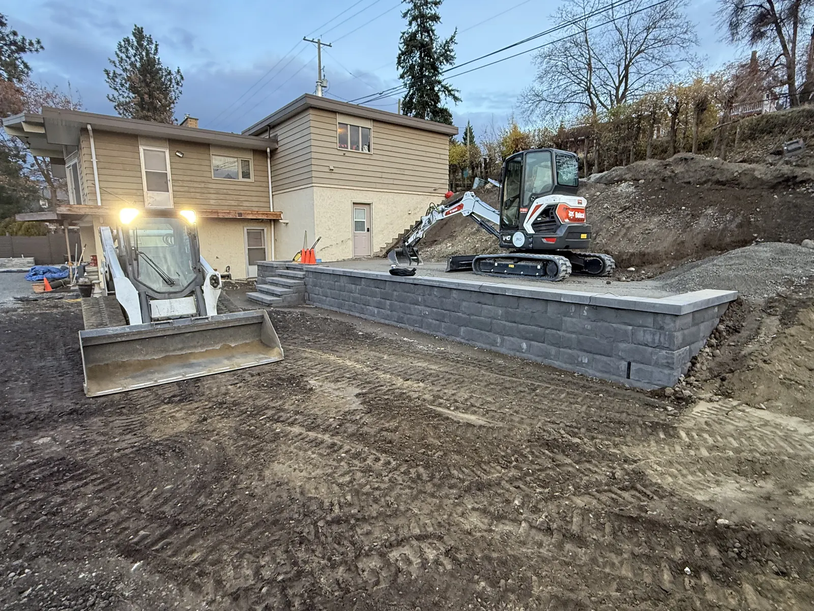 New block retaining wall with an excavator and track loader on site