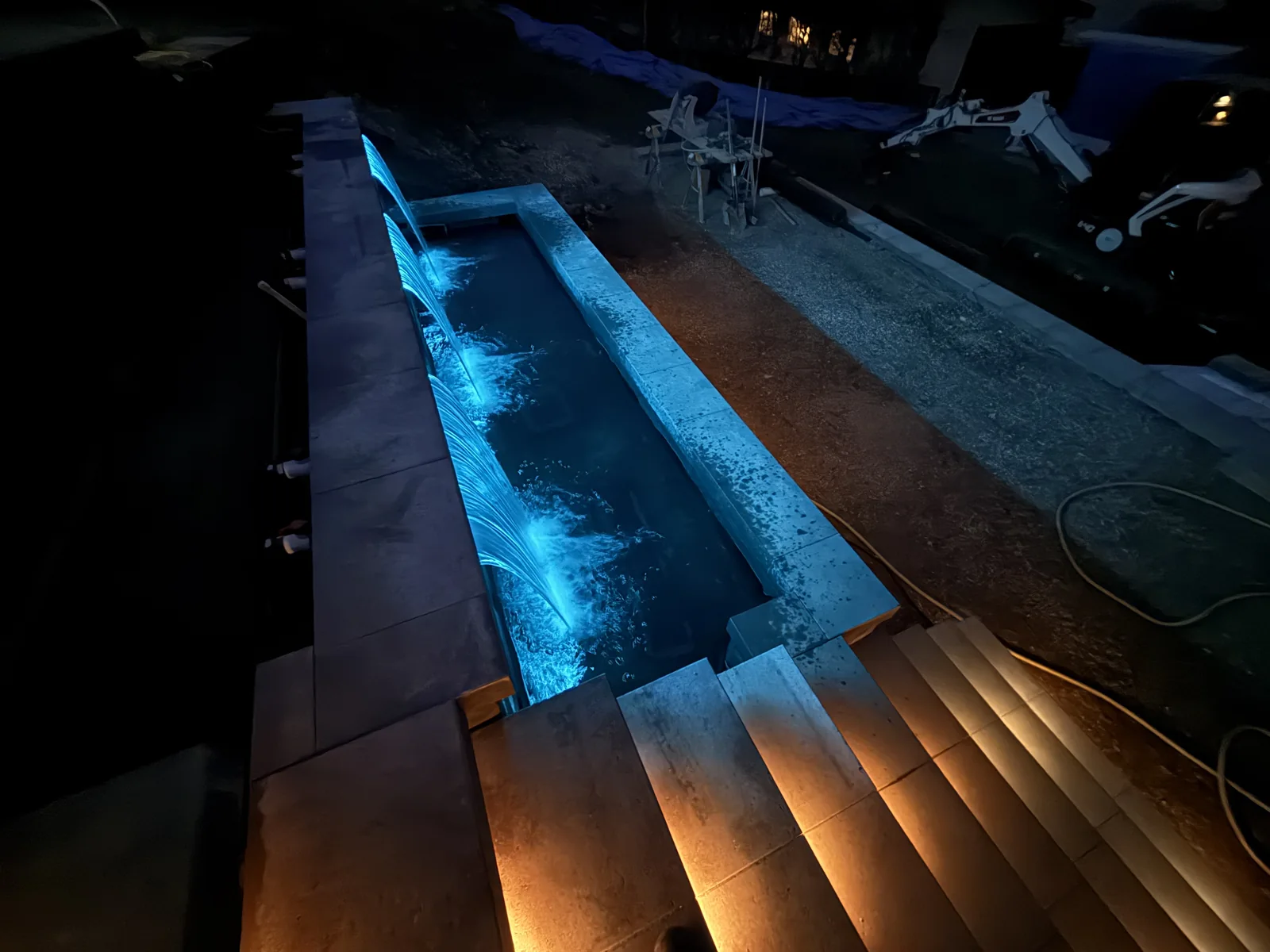 Blue lit water feature basin beside warm step lighting