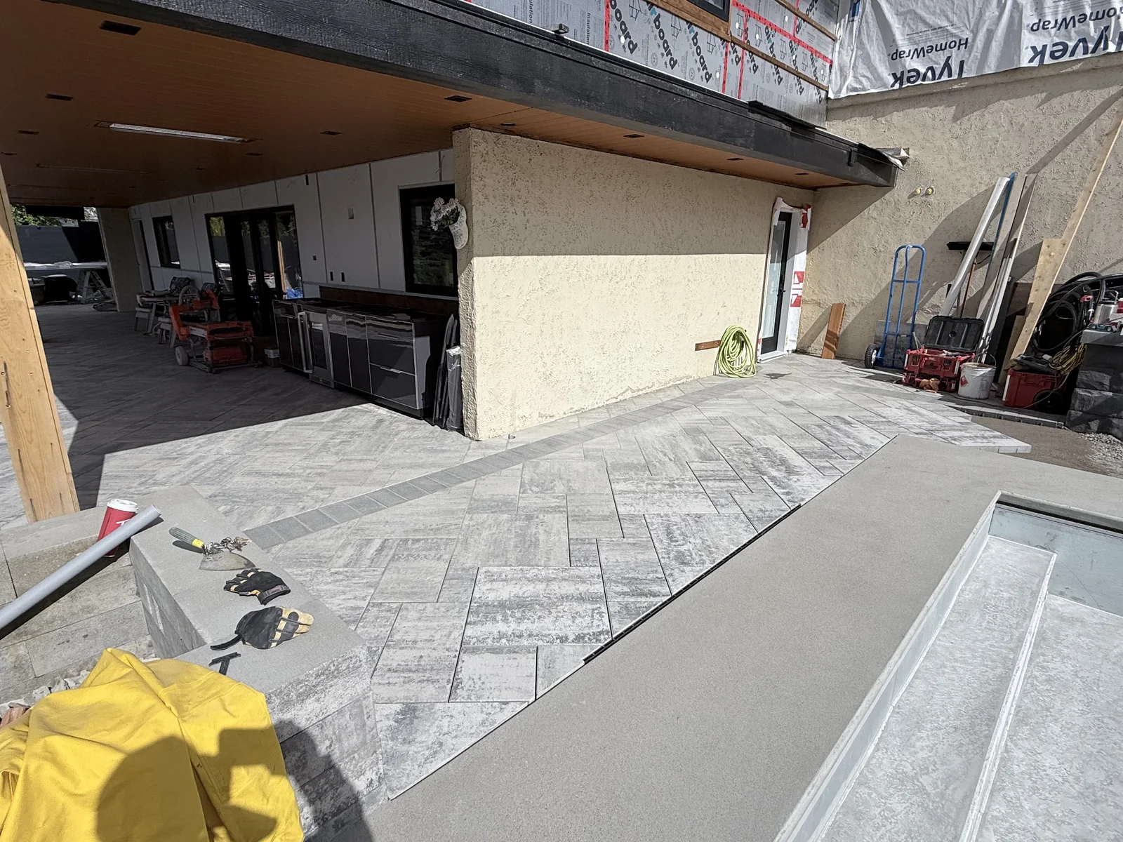 Paver patio laid along the house while the pool coping goes in