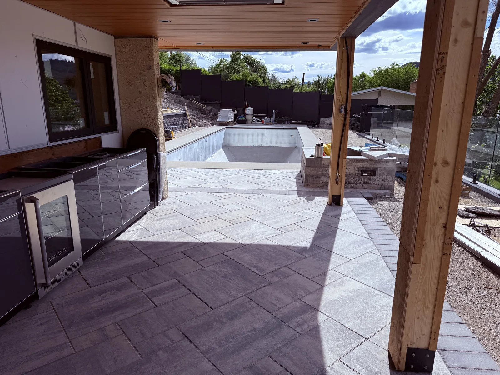 Outdoor kitchen under the covered patio with pavers running out to the pool
