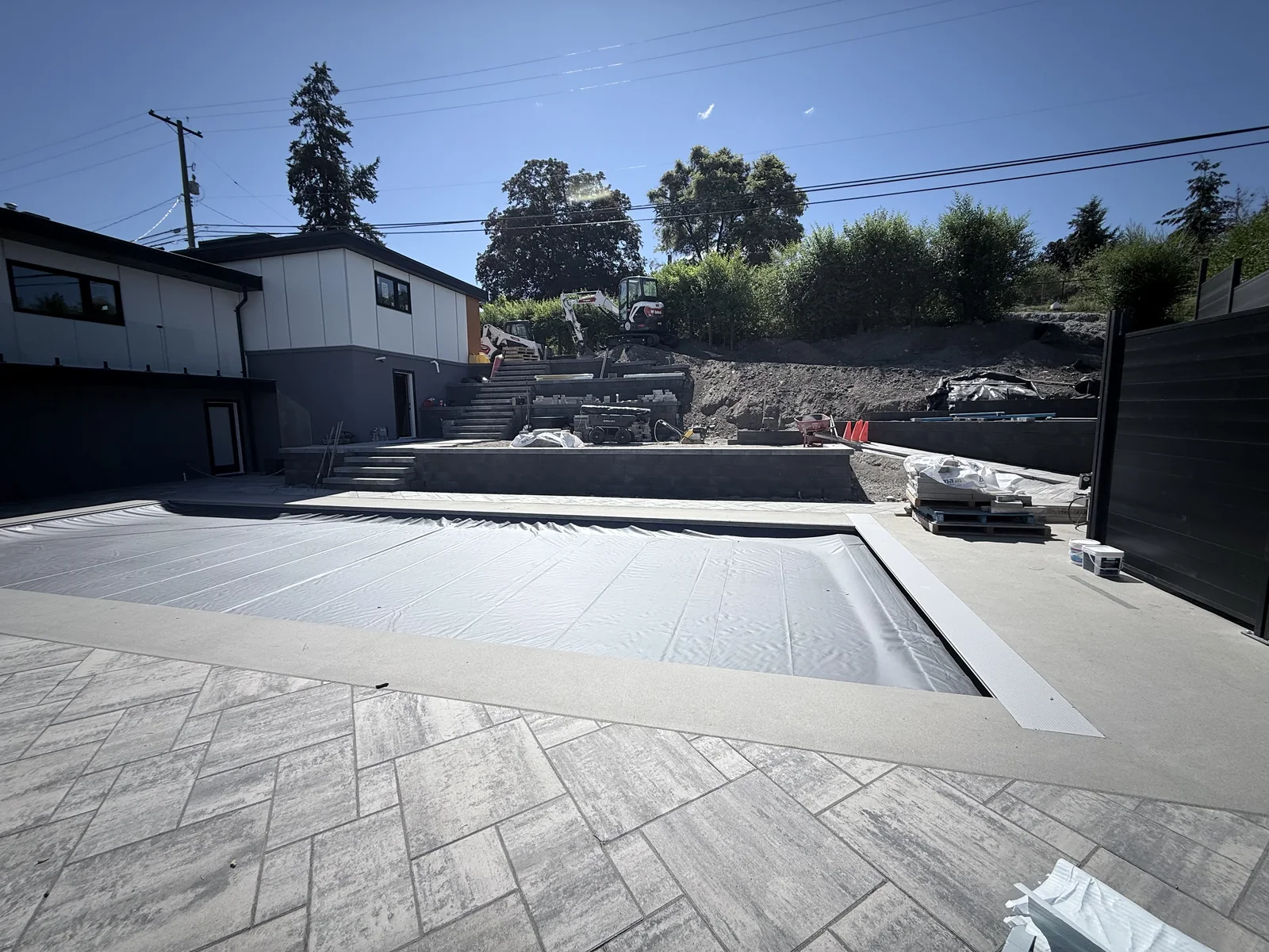 Pool with its safety cover on, coping and paver deck complete