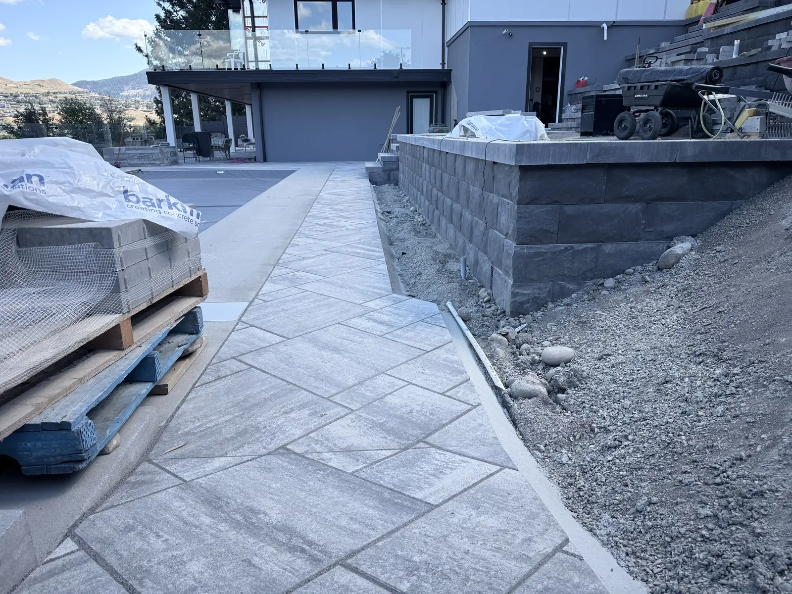 Paver walkway running between the house and a new block retaining wall