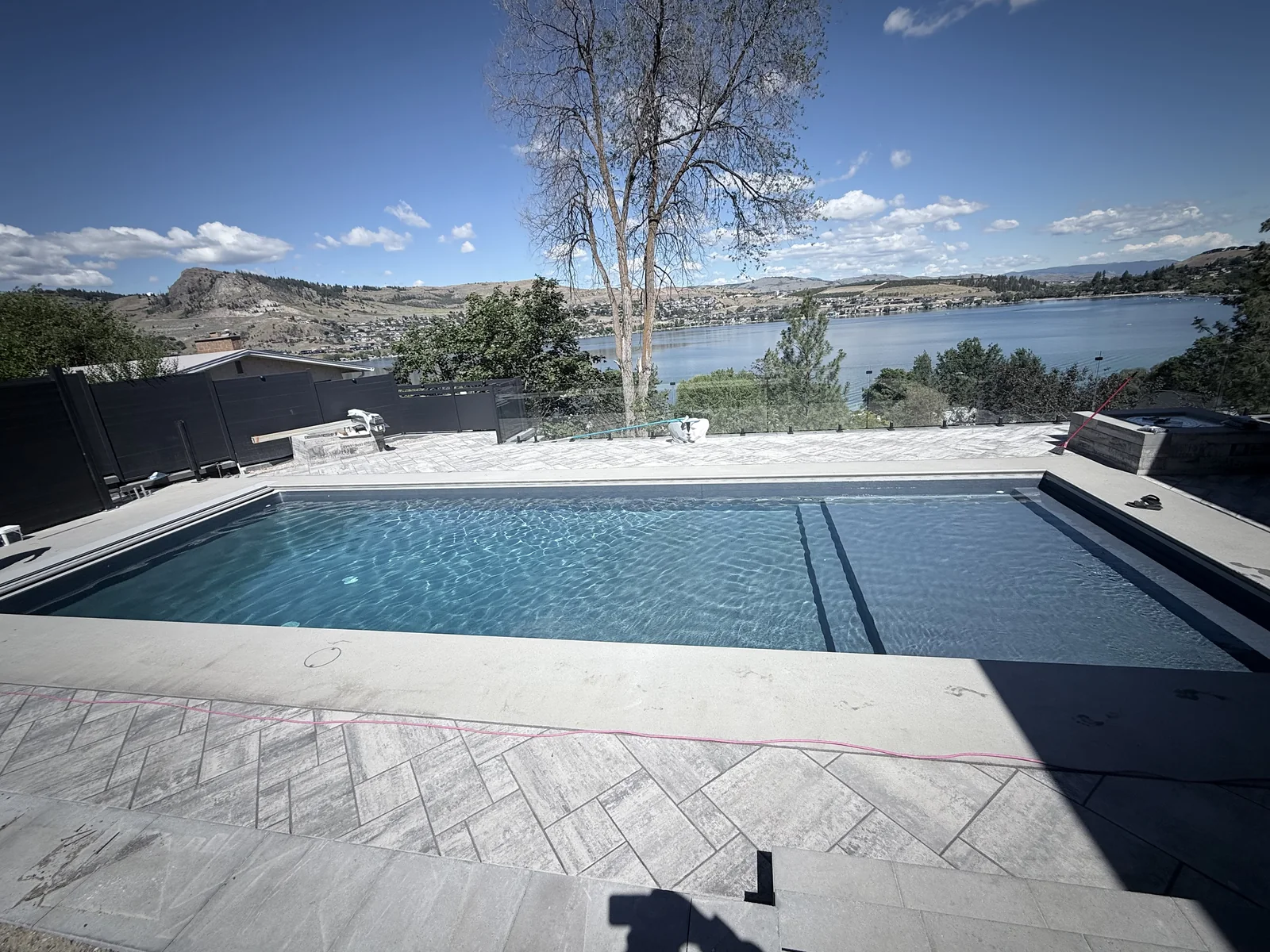 Filled pool framed by large format pavers with the lake beyond
