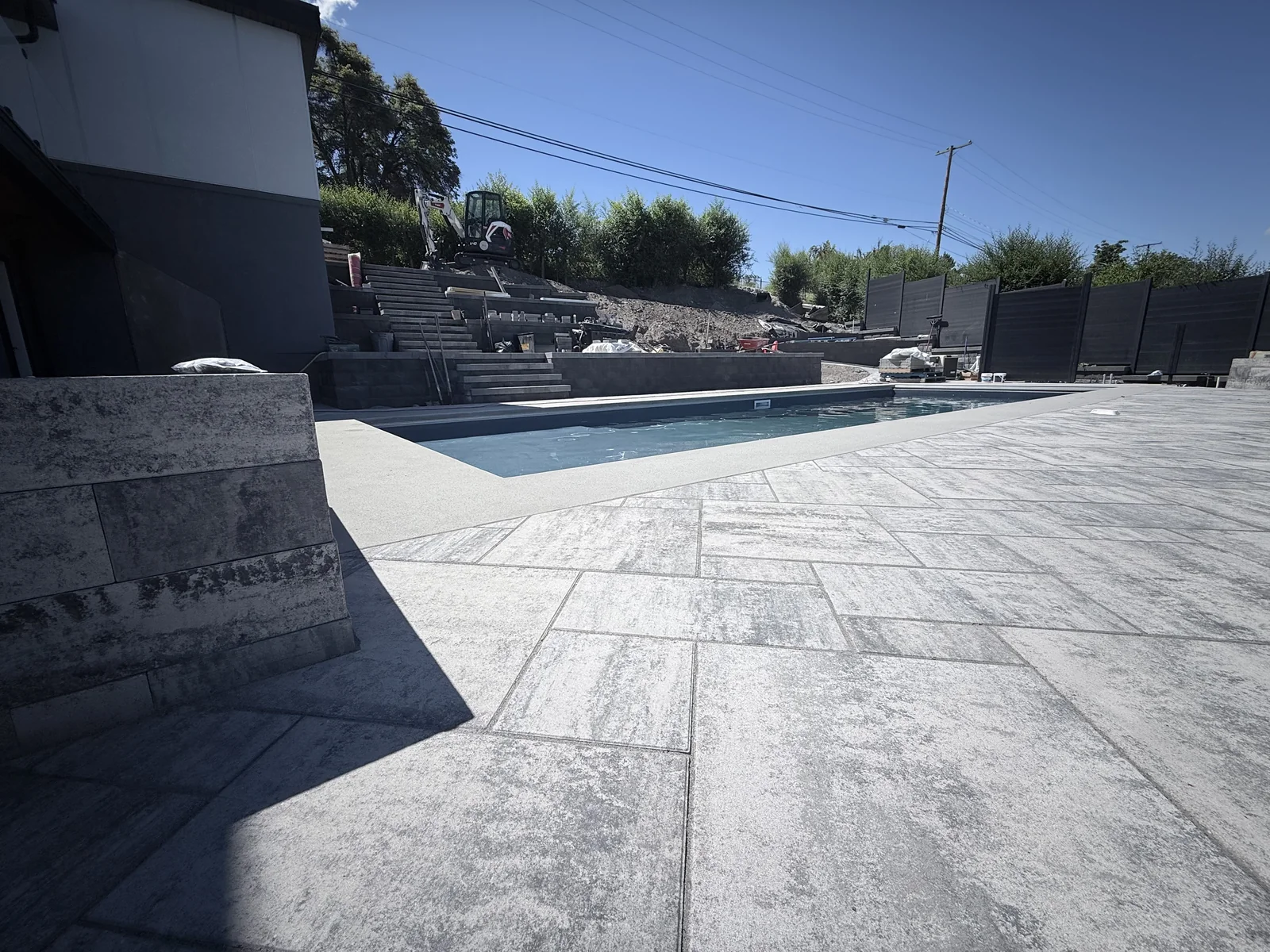 Wide paver pool deck beside a stone clad feature column
