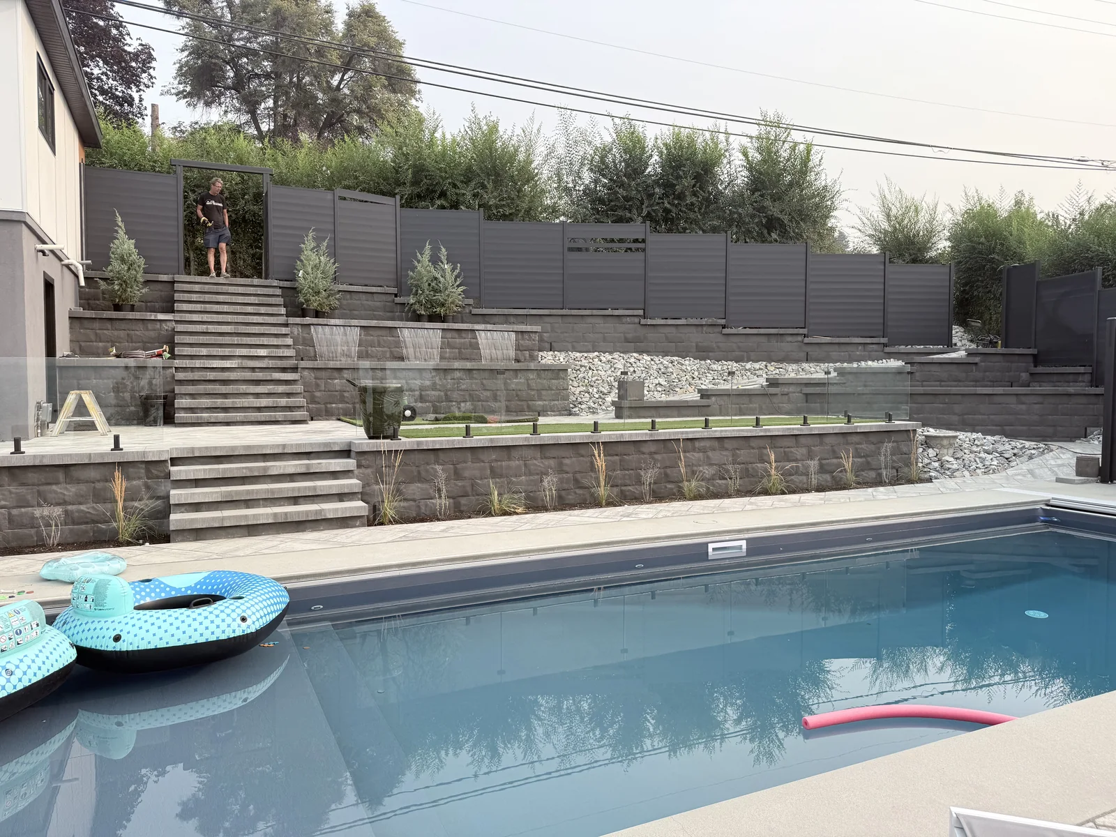 Pool with terraced retaining walls, stairs and three sheet water features behind it